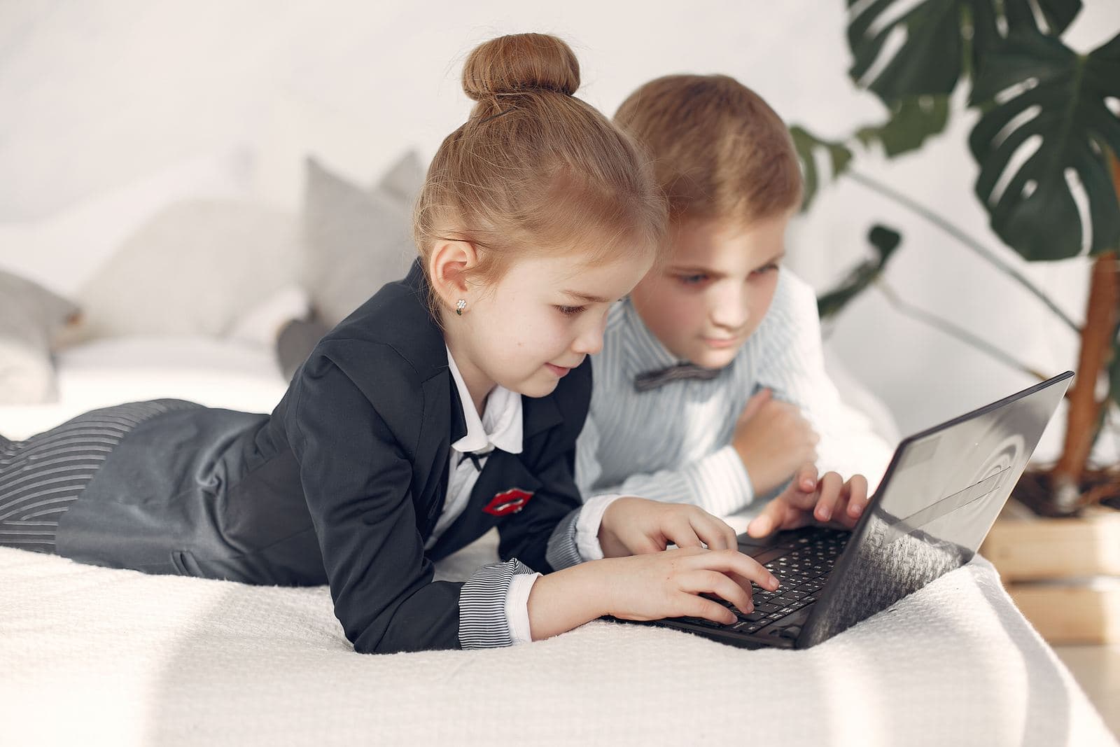 Dwoje dzieci wspólnie pracuje przy laptopie